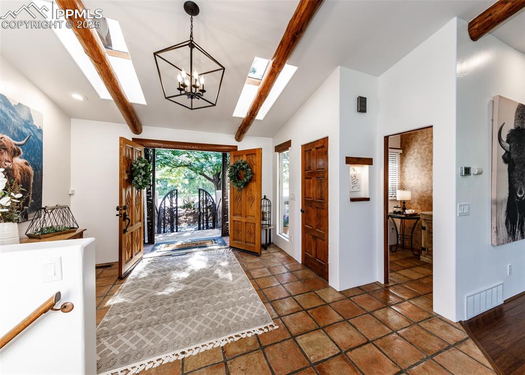 Image 6 of 50: Entryway featuring a skylight and a chandelier