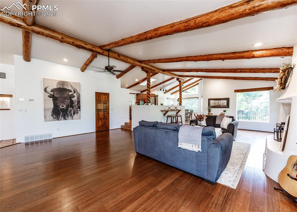 Image 8 of 50: Living area with beamed ceiling, wood finished floors, ceiling fan, recesse