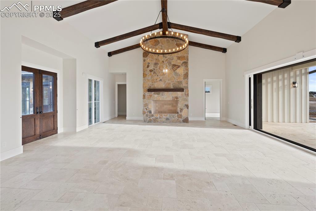 Image 12 of 47: Unfurnished living room with baseboards, high vaulted ceiling, and a chande