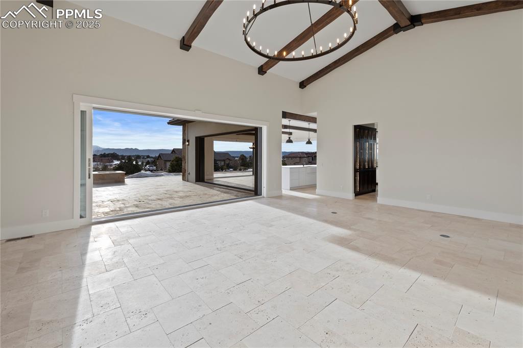 Image 15 of 47: Unfurnished living room featuring baseboards, high vaulted ceiling, a chand