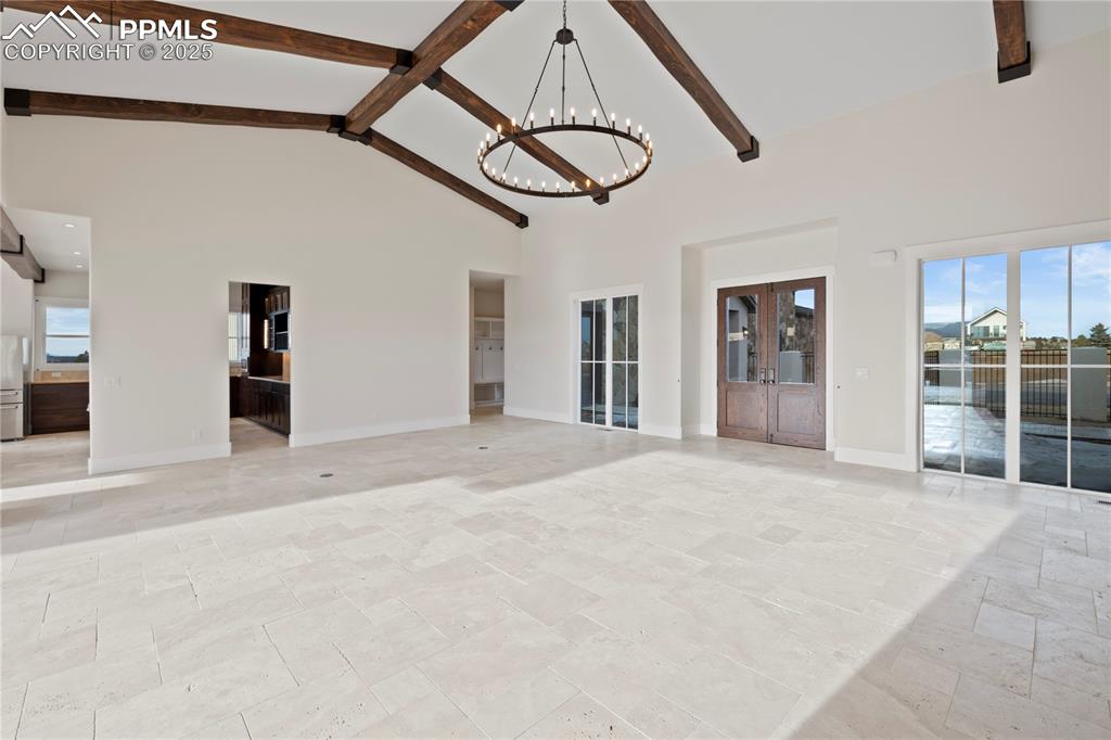 Image 16 of 47: Spare room with high vaulted ceiling, a chandelier, beamed ceiling, and ple