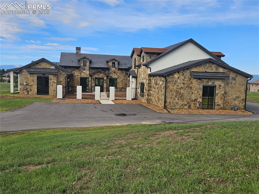 Image 2 of 47: View of front facade featuring stone siding, a fenced front yard, a gate, a