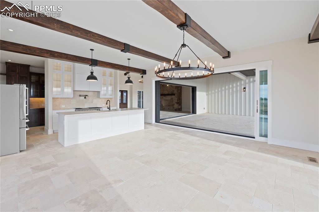 Image 20 of 47: Kitchen featuring a notable chandelier, light countertops, freestanding ref
