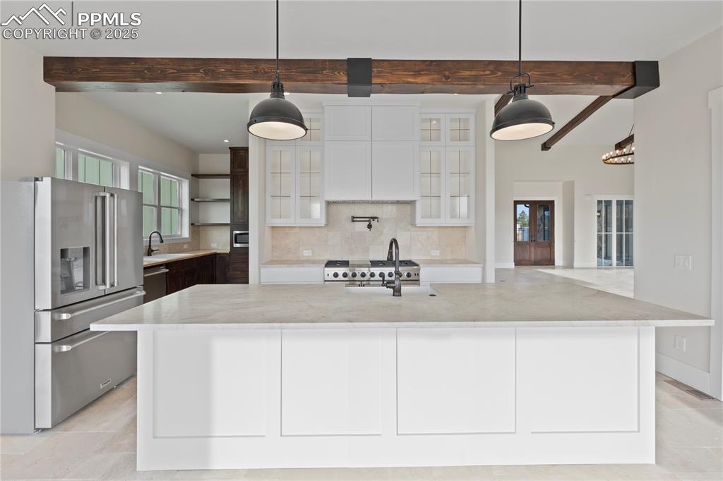 Image 23 of 47: Kitchen with stainless steel appliances, beam ceiling, white cabinetry, a s