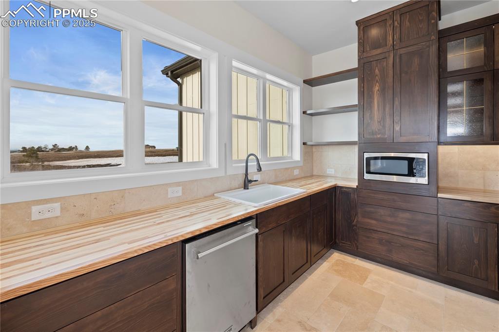 Image 24 of 47: Kitchen featuring wooden counters, a sink, dark brown cabinetry, and applia