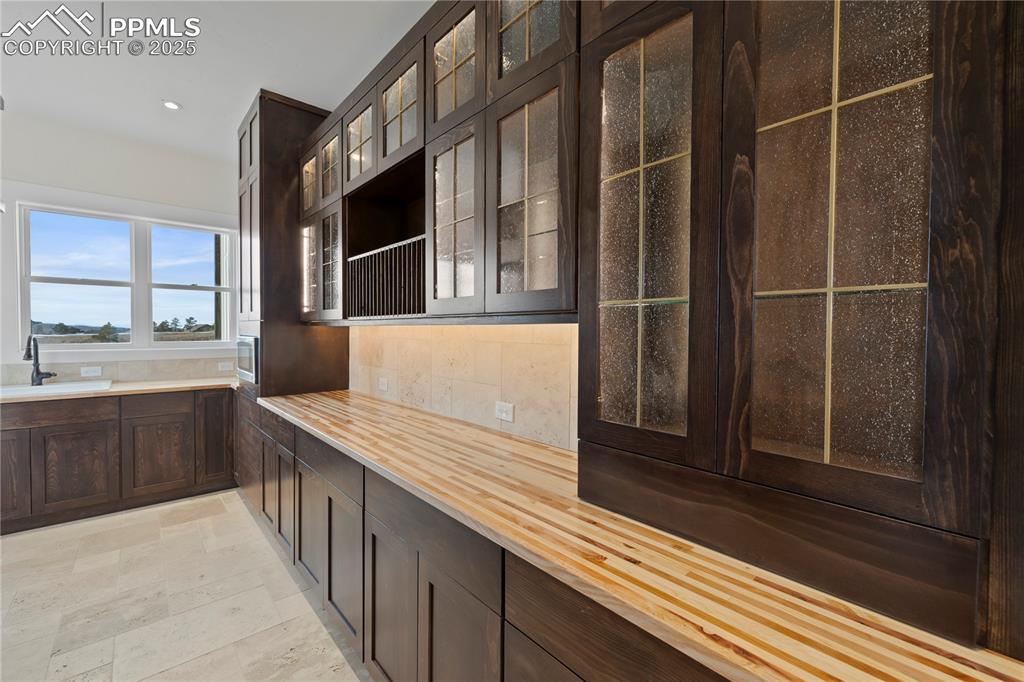 Image 25 of 47: Kitchen featuring wood counters, recessed lighting, dark brown cabinetry, g