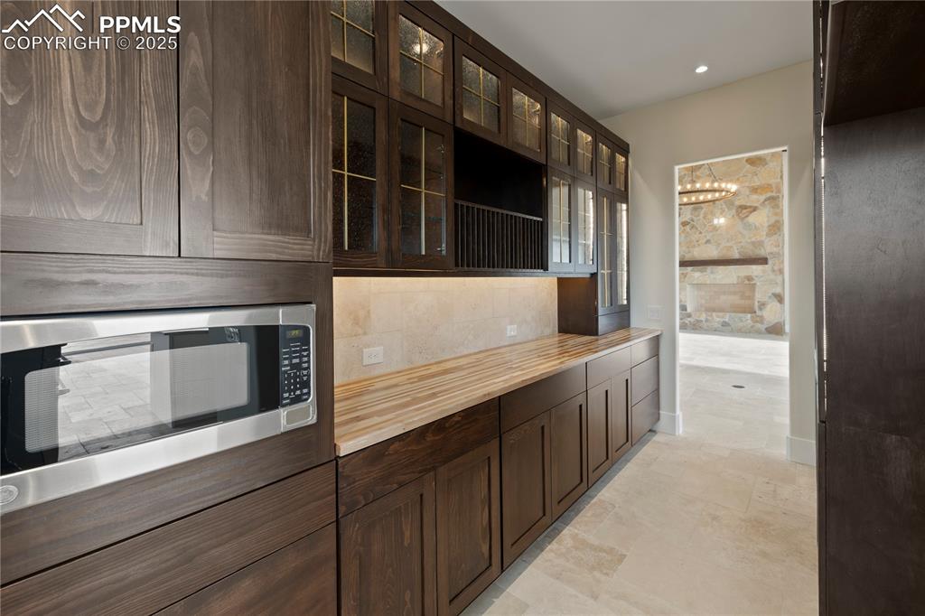 Image 27 of 47: Kitchen with a chandelier, dark brown cabinetry, butcher block countertops,