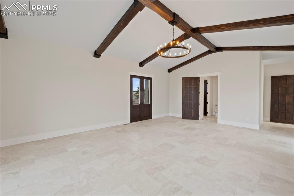 Image 29 of 47: Unfurnished living room featuring lofted ceiling with beams, baseboards, an