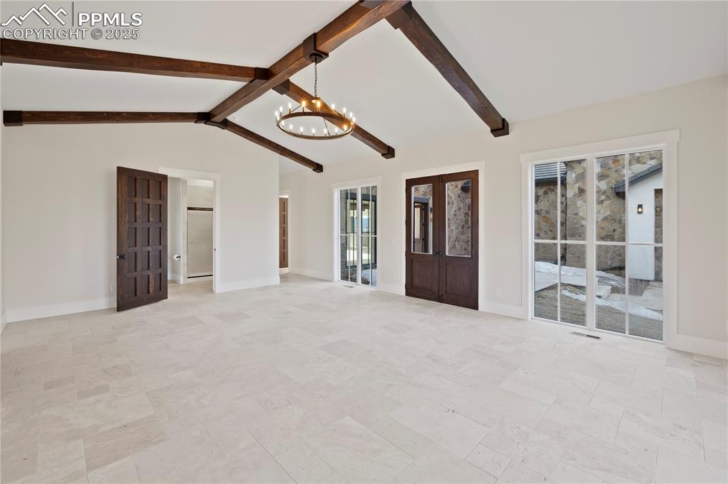 Image 30 of 47: Unfurnished living room with lofted ceiling with beams, a notable chandelie