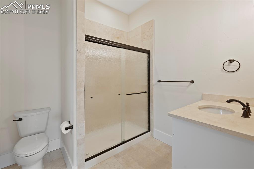 Image 32 of 47: Full bath with toilet, vanity, a stall shower, and tile patterned flooring