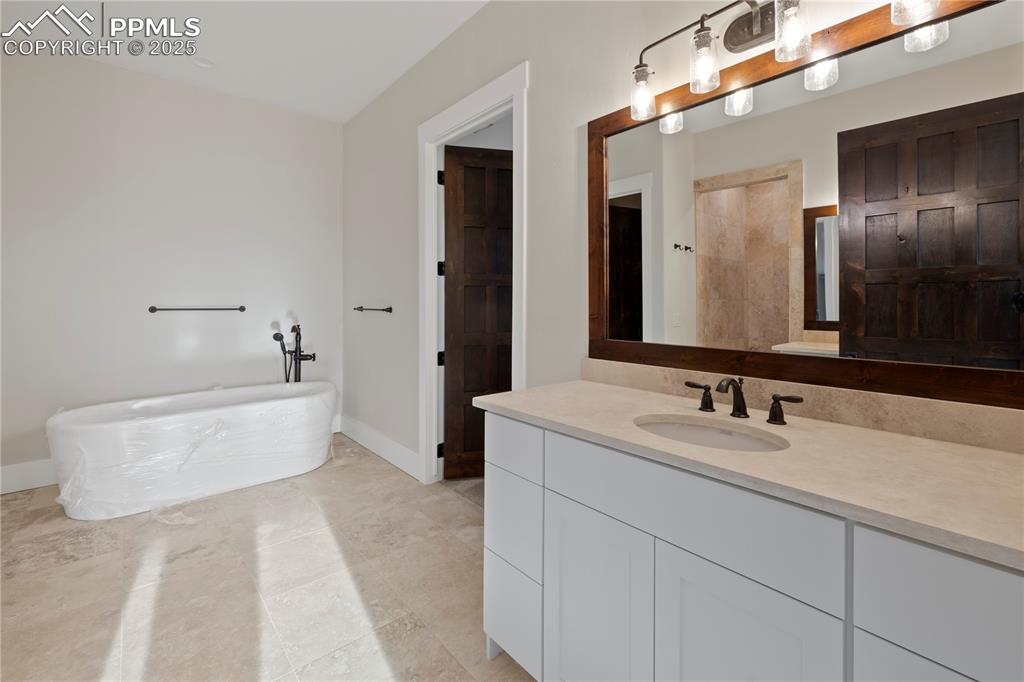 Image 36 of 47: Bathroom with baseboards, a freestanding bath, and vanity