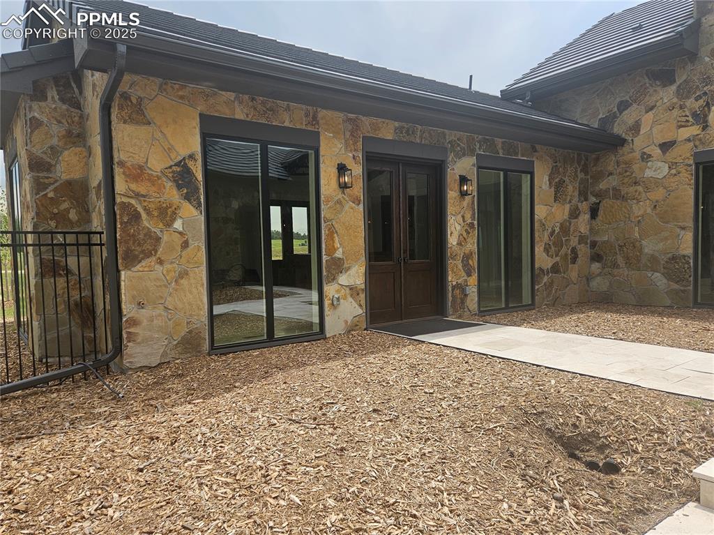 Image 4 of 47: Back of house featuring stone siding and french doors