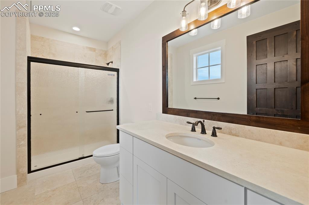 Image 41 of 47: Bathroom with vanity, toilet, tile patterned floors, and a shower stall