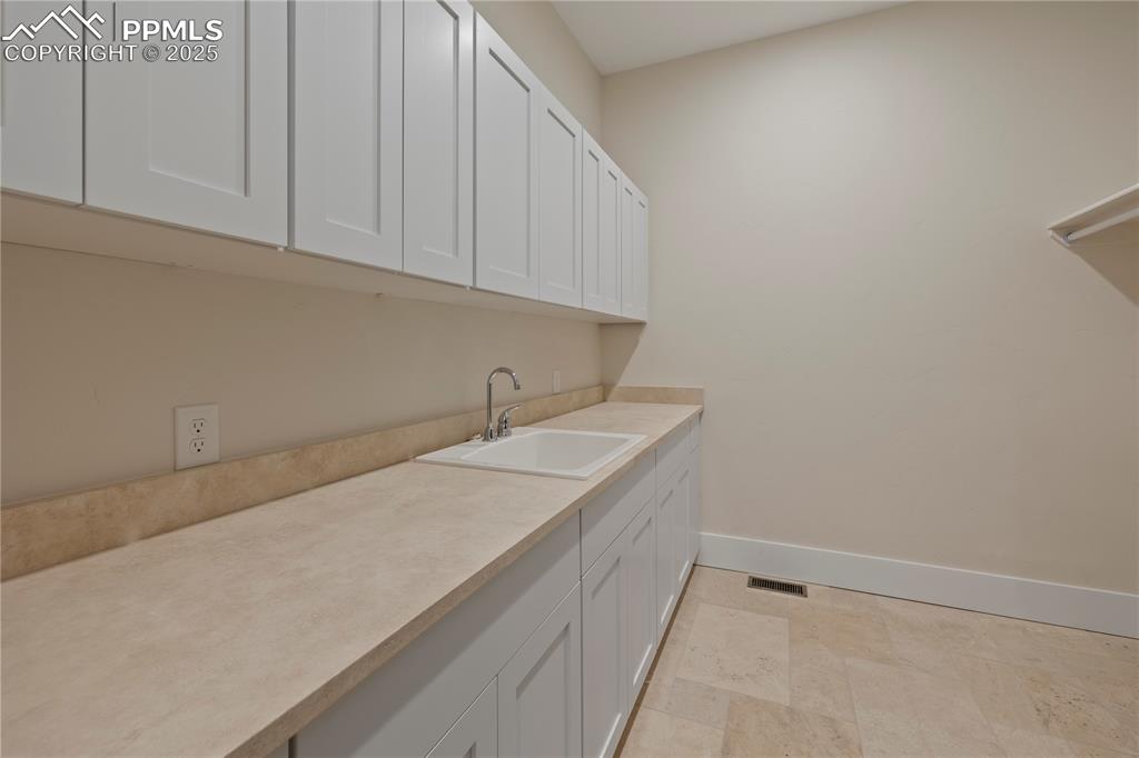 Image 42 of 47: Laundry area with a sink, baseboards, and visible vents
