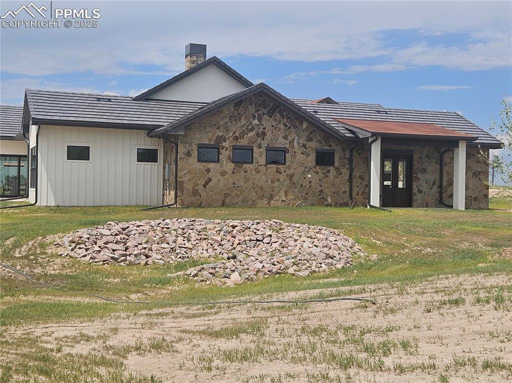 Image 47 of 47: Rear view of property with a chimney and stone siding