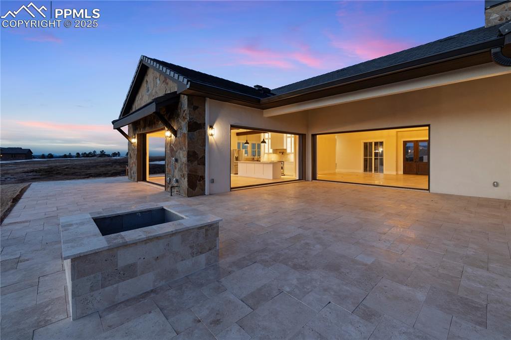 Image 8 of 47: Back of house with stucco siding, a patio, and stone siding