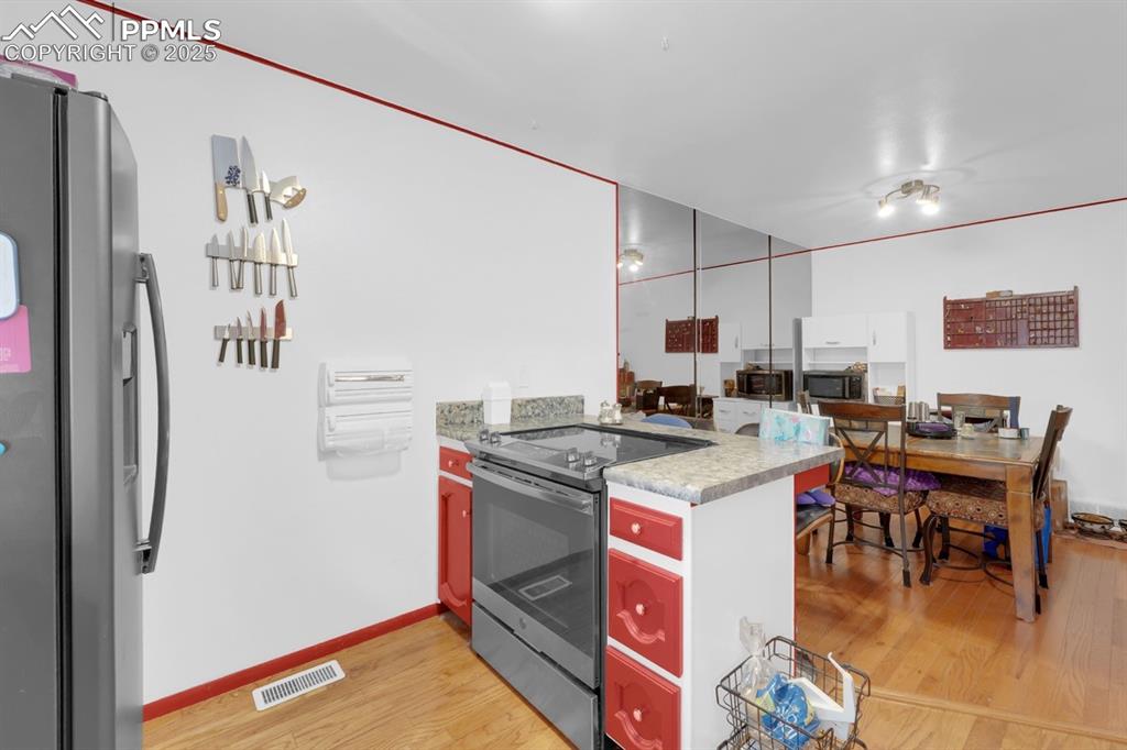 Image 10 of 27: Kitchen with stainless steel appliances, light wood-style flooring, a penin