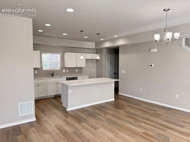 Image 12 of 42: Open-concept space featuring wood-finish flooring, white cabinetry, a kitch