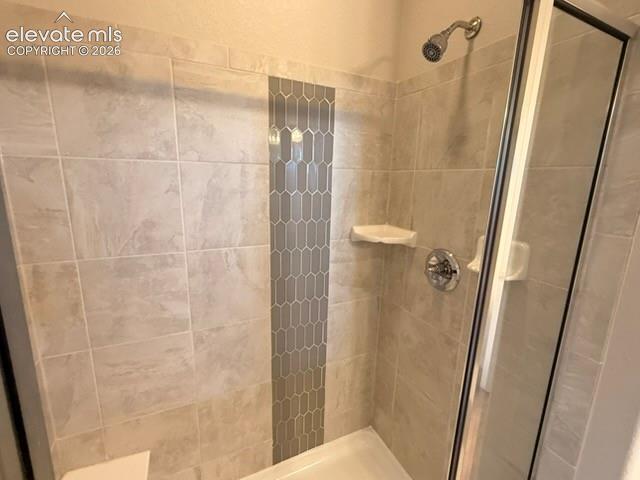 Image 15 of 42: Tiled shower with a decorative vertical accent strip, chrome fixtures, and