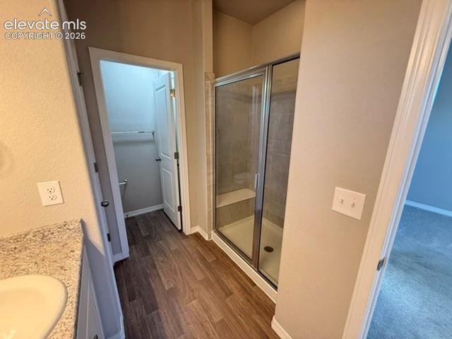 Image 16 of 42: Wood-finish flooring leading to a glass-enclosed shower with a built-in ben