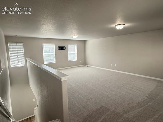 Image 23 of 42: Spacious room featuring carpeting, multiple windows with blinds, a partial