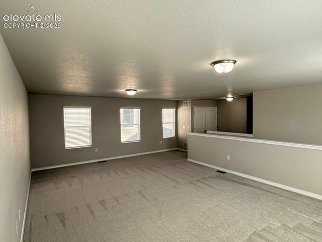 Image 24 of 42: Carpeted open-concept space featuring multiple windows with blinds, neutral