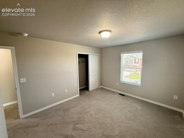 Image 29 of 42: Neutral tone wall paint with a textured ceiling, carpeted flooring, window 