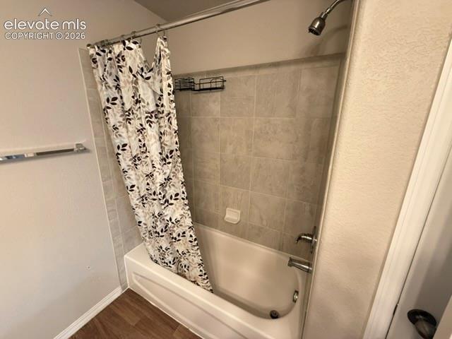 Image 33 of 42: Bathtub with tiled surround, brushed nickel fixtures, and wood-finish floor