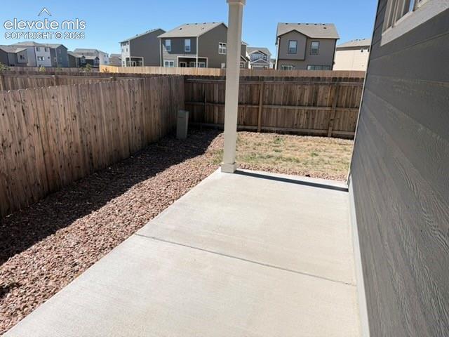 Image 34 of 42: Concrete patio with a wood privacy fence, gravel landscaping, and siding ex