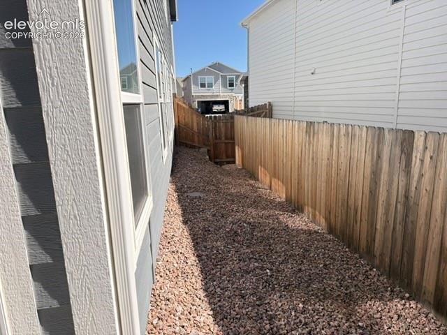 Image 35 of 42: Gravel pathway alongside a home with horizontal siding and multiple windows