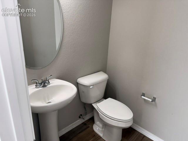 Image 4 of 42: Pedestal sink with chrome faucet, oval mirror, white toilet, and wood-finis