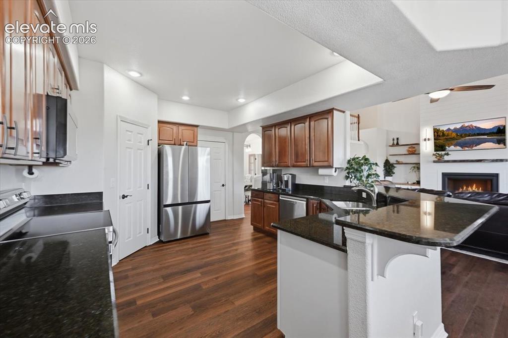 Image 9 of 36: Kitchen featuring wood-finish flooring, dark stone countertops, stainless s
