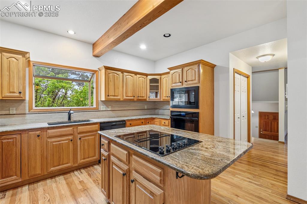 Image 11 of 48: Kitchen with black appliances, a sink, light wood finished floors, light st