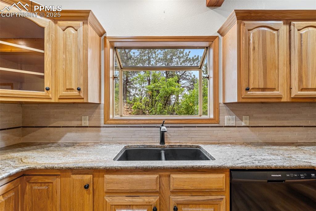 Image 12 of 48: Kitchen featuring dishwasher, a sink, tasteful backsplash, and light stone