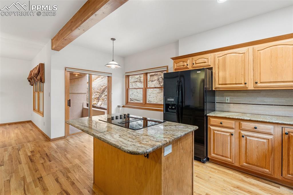 Image 14 of 48: Kitchen featuring black appliances, light stone countertops, light wood-sty