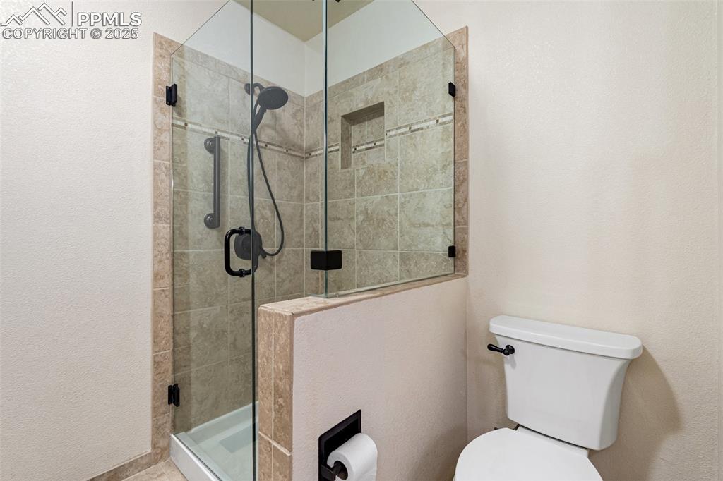 Image 21 of 48: Bathroom with toilet and a stall shower