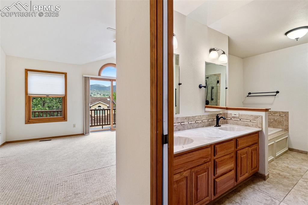 Image 23 of 48: Full bathroom with double vanity, a bath, and baseboards