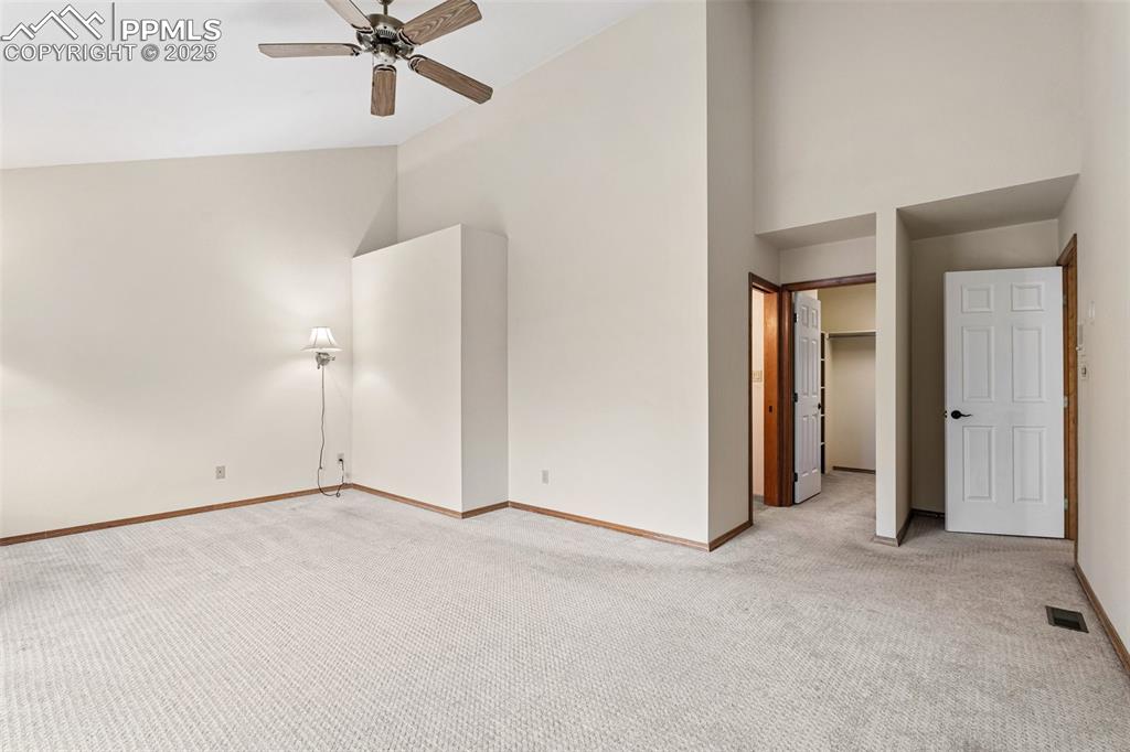 Image 28 of 48: Unfurnished bedroom featuring light carpet, high vaulted ceiling, baseboard