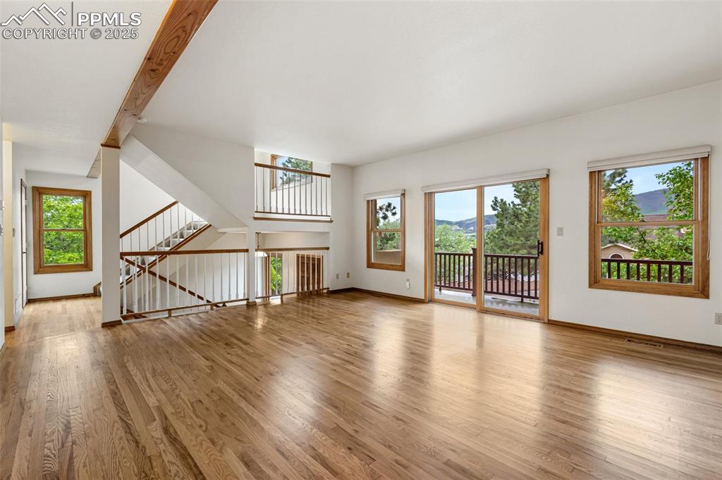 Image 3 of 48: Unfurnished living room with wood finished floors, baseboards, and stairs