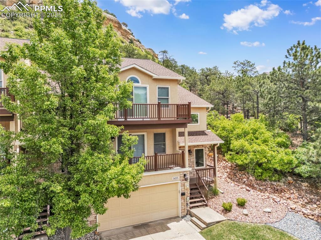 Image 43 of 48: View of front of home featuring stucco siding, a balcony, a garage, concret