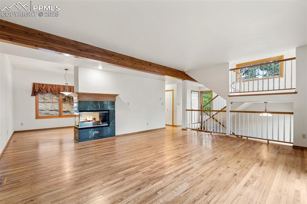Image 5 of 48: Unfurnished living room featuring wood finished floors, a fireplace, basebo