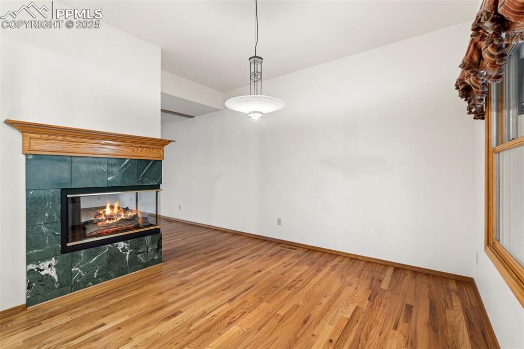 Image 6 of 48: Unfurnished living room with wood finished floors, a fireplace, and baseboa