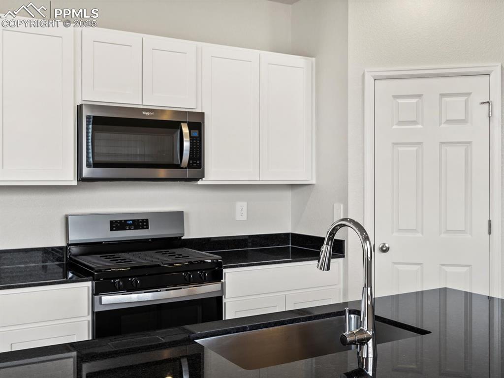 Image 3 of 24: Kitchen featuring appliances with stainless steel finishes, dark stone coun