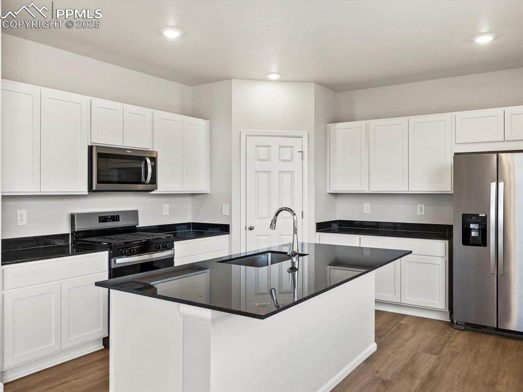 Image 5 of 24: Kitchen featuring appliances with stainless steel finishes, white cabinets,