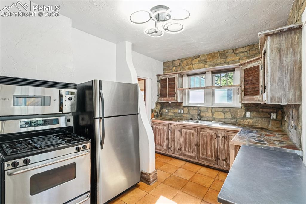 Image 13 of 36: Custom kitchen with gas burning stove, stone countertops and custom cabinet
