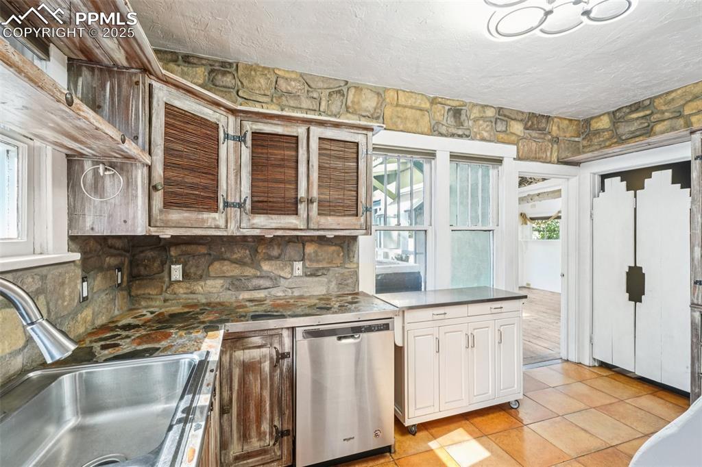 Image 14 of 36: Custom kitchen with stone countertops with a stainless steel sink and appli