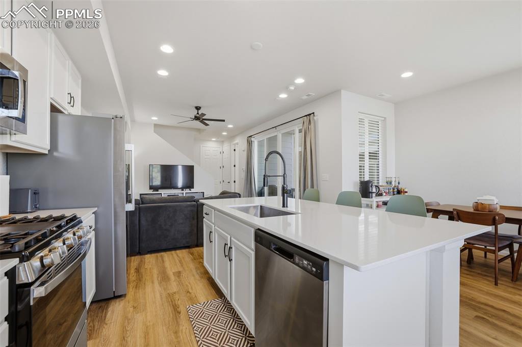 Image 9 of 31: Kitchen featuring white cabinetry, open floor plan, appliances with stainle