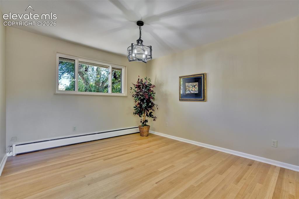 Image 12 of 50: Room featuring wood-finish flooring, a metal cage-style chandelier, and a h