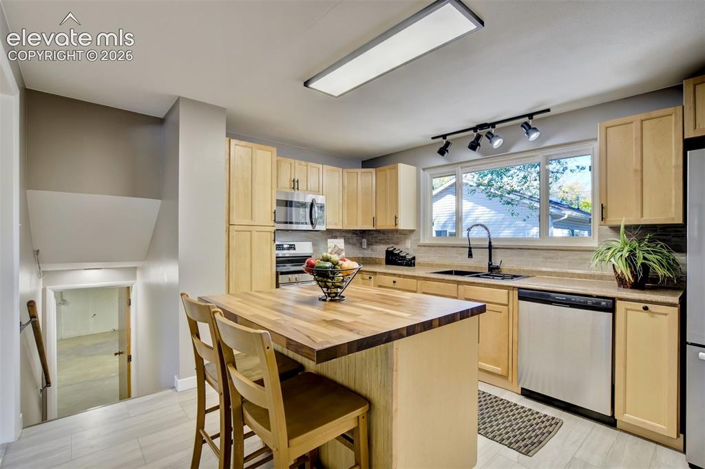 Image 14 of 50: Kitchen featuring light wood cabinetry, butcher-block island countertop, st