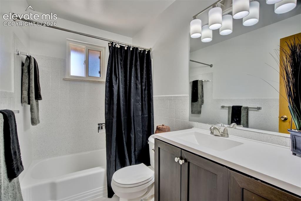 Image 18 of 50: Bathroom featuring a vanity with dark cabinetry, a solid-surface countertop